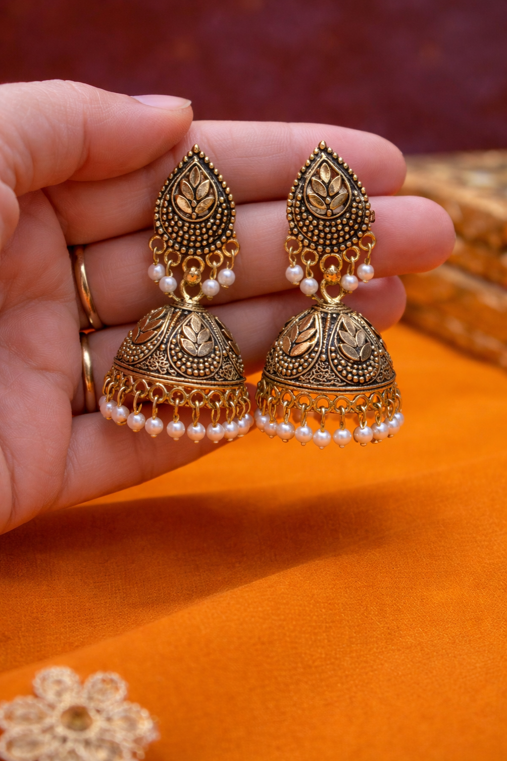 Antique gold jhumka earrings for women with pearl drops and leaf motif