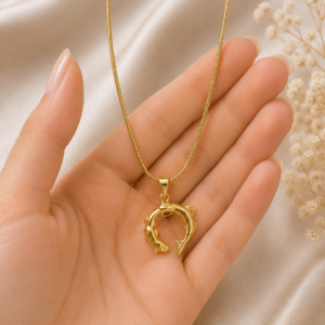 Woman wearing a gold-toned dolphin pendant necklace with a minimalist elegant design.