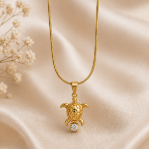 Woman wearing a gold-toned sea turtle pendant necklace with sparkling crystal detail